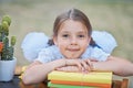 Portrait of a beautiful young first-grader sitting at a desk on the background autumn park. Farewell Bell. day of knowledge. begin