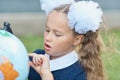 Portrait of a beautiful young first-grader sitting at a desk on the background autumn park. Farewell Bell. day of knowledge. begin