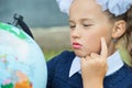 Portrait of a beautiful young first-grader sitting at a desk on the background autumn park. Farewell Bell. day of knowledge. begin