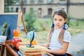 Portrait of a beautiful young first-grader sitting at a desk on the background autumn park. Farewell Bell. day of knowledge. begin