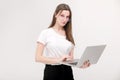 Portrait of a beautiful young girl with blond hair in glasses and a white T-shirt working or studying on a laptop Royalty Free Stock Photo