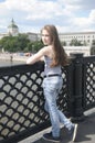 Portrait of beautiful young girl on the bridge blue sky background with blowing hair in wind