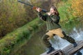 Portrait of a beautiful young girl in camouflage hunter with shotgun on a background of the river Royalty Free Stock Photo