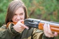 Portrait of a beautiful young girl in camouflage hunter with shotgun