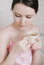 Cup of coffee in hands of young woman in the morning. Portrait of a beautiful young girl drinking coffee in bed.