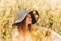 Portrait of a beautiful young girl in a hat against the background of a rapeseed field