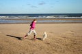 Portrait of a beautiful young girl and her puppy running on the beach