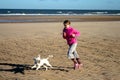 Portrait of a beautiful young girl and her puppy running on the beach