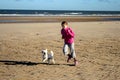 Portrait of a beautiful young girl and her puppy running on the beach