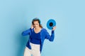 Portrait of beautiful young girl in stylish clothes posing in headphones and vinyl over blue background. DJ Royalty Free Stock Photo