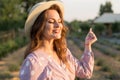 Portrait of a beautiful young girl in a summer dress and hat in a lavender field at sunset Royalty Free Stock Photo