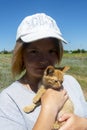 Portrait of a beautiful young girl in a white cap. Red kitten in the hands of his mistress. Walk with your pet in the summer Royalty Free Stock Photo