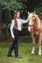 Portrait beautiful young girl in white shirt and black pants with beauty long hair next horse in forest. Fashionable elegance woma Royalty Free Stock Photo