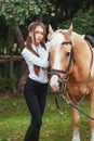 Portrait beautiful young girl in white shirt and black pants with beauty long hair next horse in forest. Fashionable elegance woma Royalty Free Stock Photo