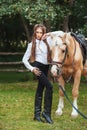 Portrait beautiful young girl in white shirt and black pants with beauty long hair next horse in forest. Fashionable elegance woma Royalty Free Stock Photo