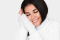 Portrait of beautiful young happy dreamy woman with closed eyes in white sweater on light grey background. Royalty Free Stock Photo