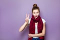 Portrait of beautiful young happy smiling woman, showing two fingers or victory gesture, dressed white t-shirt and red scarf on pu Royalty Free Stock Photo