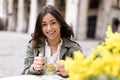 Portrait of beautiful young hispanic woman drinking a cup of camomile tea in cafeteria with mimosa flower bouquet on the table Royalty Free Stock Photo