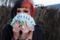 Portrait of a beautiful young individual, eccentric woman, holding many euro banknotes. Basic income citizen money in hand Royalty Free Stock Photo