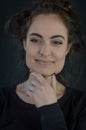 Portrait of a beautiful young Italian woman with coarsely gathered hair holding her chin with her fingers while she is smiling Royalty Free Stock Photo