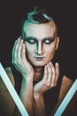 Portrait of beautiful young man with modern hairstyle, artistic multicolor makeup. Studio shot.