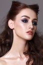 Portrait of a beautiful young model with professional makeup, trendy colorful smoky eyes and wavy hairdo