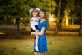 Portrait of beautiful young mother hugging first-grader daughter in festive school uniform on background autumn park. Royalty Free Stock Photo