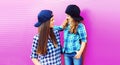 Portrait of beautiful young mother with little girl child wearing checkered shirts, baseball cap in city on pink background Royalty Free Stock Photo