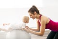 A Portrait of beautiful young mother in sports wear with her charming little baby in training session Royalty Free Stock Photo