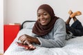 Portrait of beautiful young muslim black woman relaxing on bed at home. Royalty Free Stock Photo