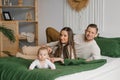 Portrait of beautiful young parents and a cute child looking into the camera and smiling while lying together in bed Royalty Free Stock Photo