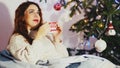 Portrait of beautiful young red-haired woman wearing stylish christmas sweater and socks sitting on comfortable sofa and Royalty Free Stock Photo