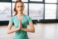 Portrait of beautiful young redhead woman in sportswear practicing yoga and looking at camera sitting in lotus position Royalty Free Stock Photo