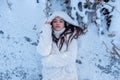 Portrait of beautiful, young, secy, cute, brunette woman, freezing in the cold winter in white coat and hood, lying surreal like Royalty Free Stock Photo