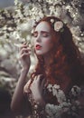 Portrait of a beautiful young sensual woman with very long red curly hair in spring flowers. Colors of spring . Royalty Free Stock Photo