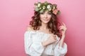 Portrait of beautiful young sexual sensual woman with perfect skin make up curly hair and flowers on head on pink background. Wrea Royalty Free Stock Photo