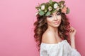 Portrait of beautiful young sexual sensual woman with perfect skin make up curly hair and flowers on head on pink background. Wrea Royalty Free Stock Photo