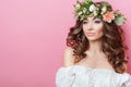 Portrait of beautiful young sexual sensual woman with perfect skin make up curly hair and flowers on head on pink background. Wrea Royalty Free Stock Photo