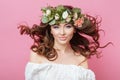 Portrait of beautiful young sexual sensual woman with perfect skin make up streaming hair and flowers on head on pink background. Royalty Free Stock Photo