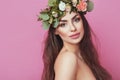 Portrait of beautiful young sexual sensual woman with perfect skin make up streaming hair and flowers on head on pink background. Royalty Free Stock Photo