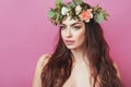 Portrait of beautiful young sexual sensual woman with perfect skin make up streaming hair and flowers on head on pink background. Royalty Free Stock Photo