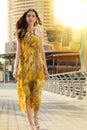 Portrait Of Beautiful Young And Slim Brunette Girl Wearing Yellow Silk Dress Waling In Dubai Marina, Soft Sunset On The Royalty Free Stock Photo