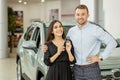 Portrait of beautiful young smiling couple holding key of their new car, auto