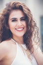 Portrait of beautiful young smiling and positive woman with curly and long hair. Outdoors Royalty Free Stock Photo