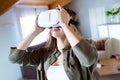 Beautiful young smiling woman using virtual reality headset at home. Royalty Free Stock Photo