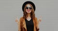 beautiful young smiling woman wearing a black round hat, brown jacket on a gray background Royalty Free Stock Photo