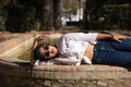 Portrait of beautiful young South American woman in white shirt, jeans and sunglasses on vacation in Europe lying next to a water Royalty Free Stock Photo