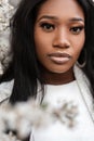 Portrait of a beautiful young tender woman near flowers on the street. Portrait of a cute african girl with clean black skin near Royalty Free Stock Photo