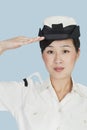 Portrait of a beautiful young US Navy officer saluting over light blue background