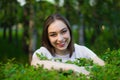 Portrait of a beautiful young woman on a background of green leaves, summer outdoors. Naturally beautiful woman smiling while